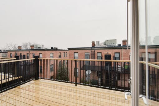 a balcony with a wooden railing and a brick building in the background