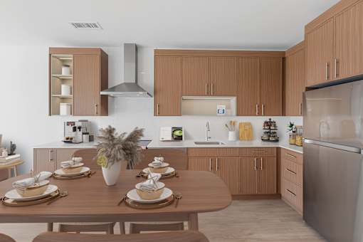 A modern kitchen with wooden cabinets and a dining table set for a meal.