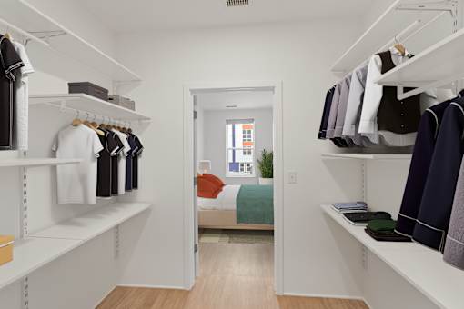 A walk in closet with clothes hanging on shelves.