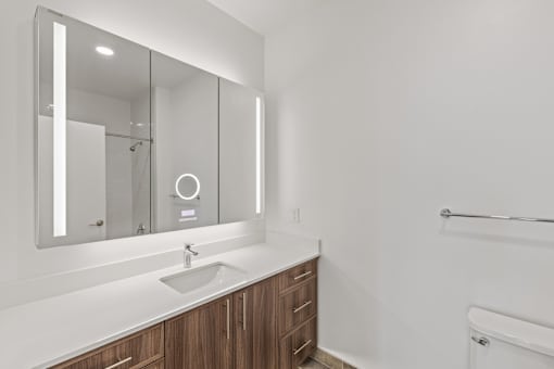 A modern bathroom with a sink, mirror, and wooden cabinets.