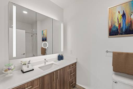A bathroom with a large mirror, a sink, and a painting on the wall.