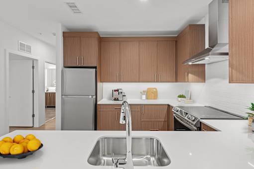 A modern kitchen with a stainless steel sink and wooden cabinets.