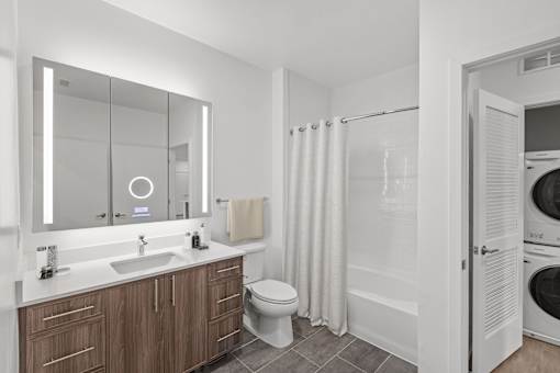 A modern bathroom with a wooden vanity and white fixtures.