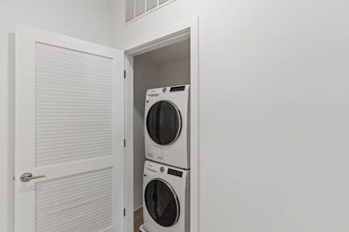 A white door is open to a small laundry room with a washer and dryer.