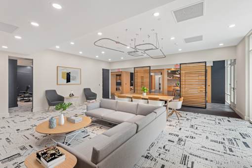 A modern living room with a grey sofa, a coffee table, and a patterned carpet.