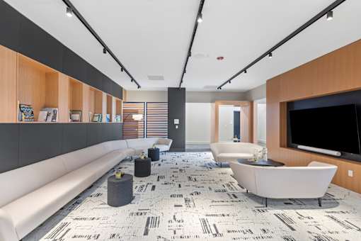 A modern living room with a white sofa, a patterned rug, and a flat-screen TV.