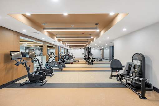 A gym with a variety of exercise equipment including treadmills, stationary bikes, and weight machines.