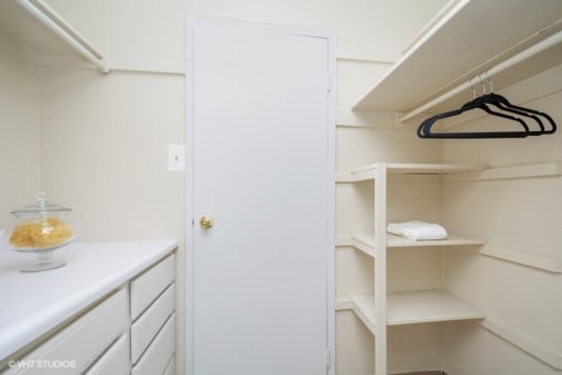 a walk in closet with white cabinets and a white door