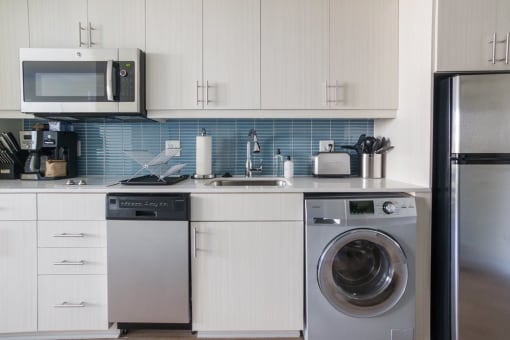 a kitchen with white cabinets and a silver washer and dryer