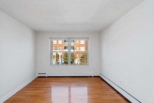 an empty room with a large window and wooden floors