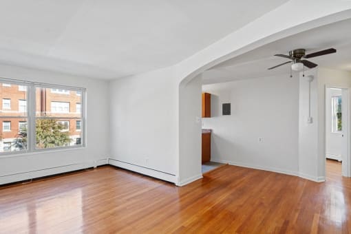an empty living room with wood floors and a ceiling fan