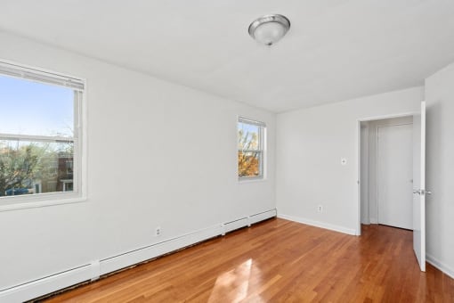 an empty living room with wood flooring and a door to a bedroom