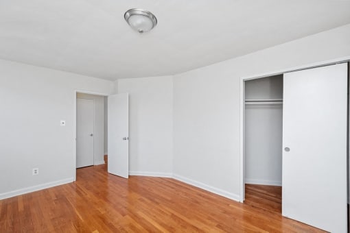 the living room with wood floors and white walls and sliding closet doors