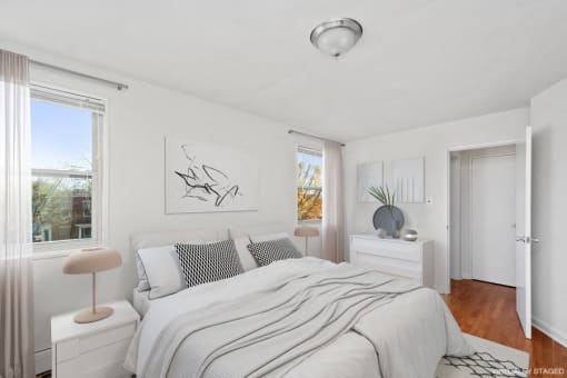 a white bedroom with a bed and two windows