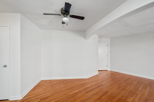an empty living room with wood floors and a ceiling fan