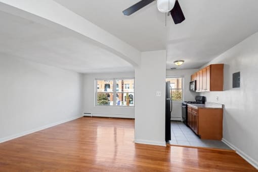 an empty living room and kitchen with wood floors and a window