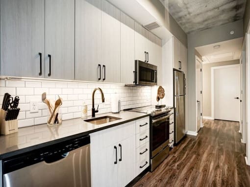A kitchen with white cabinets and black appliances at Coda on H Apartments, Washington, DC 20002