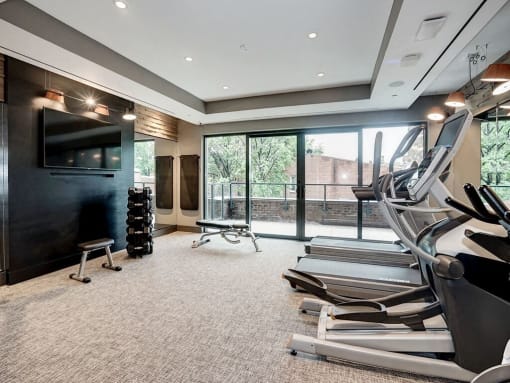 A gym with treadmills, weights, and a television at Coda on H Apartments, District of Columbia 20002