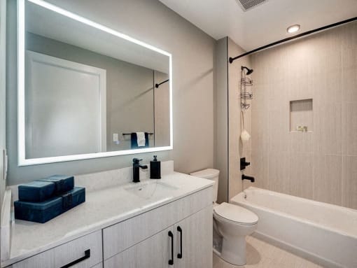 a bathroom with a toilet and a sink and a mirror at Coda on H Apartments, Washington, DC 20002
