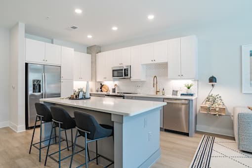 Modern kitchen with white cabinets and island seating at The Yancey Apartments, Charlotte, North Carolina