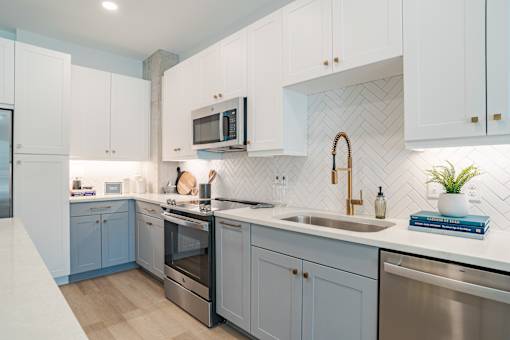 Modern kitchen with herringbone tile backsplash and blue cabinets at The Yancey Apartments, North Carolina