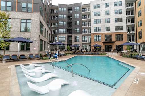 Resort style pool with sun shelf loungers and courtyard seating at The Yancey Apartments, North Carolina