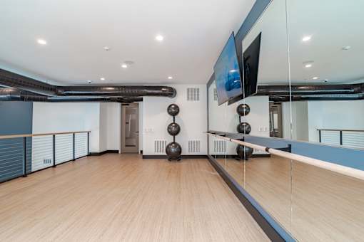 Upper level fitness studio with mirrored wall and wood flooring at The Yancey Apartments, Charlotte, 28217