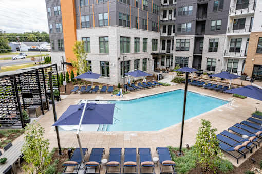 Pool deck with lounge chairs and blue umbrellas at The Yancey Apartments, Charlotte, 28217