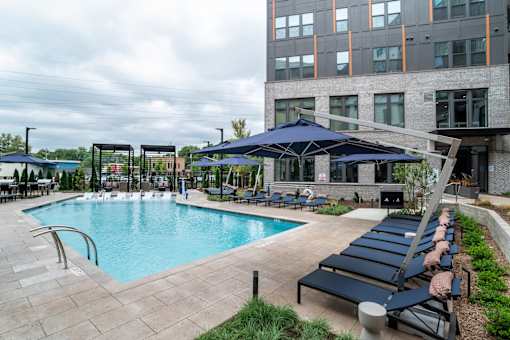Swimming pool with lounge chairs and large umbrellas at The Yancey Apartments, Charlotte