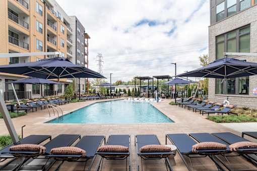 Pool area with large umbrellas and surrounding lounge chairs at The Yancey Apartments, Charlotte, North Carolina
