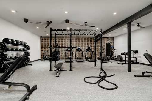 A gym with a variety of equipment including weights and a bench.