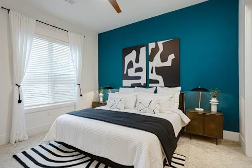 A bedroom with a bed, nightstand, and a large abstract painting on the wall at Vintage Edge Nashville Apartments, Nashville, TN