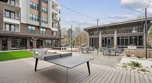 A ping pong table is in the middle of a wooden deck at Vintage Raleigh West Apartments, Raleigh