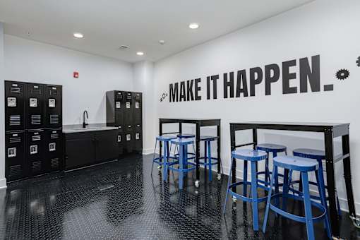 A black and white room with blue stools and a wall that says "Make it happen".