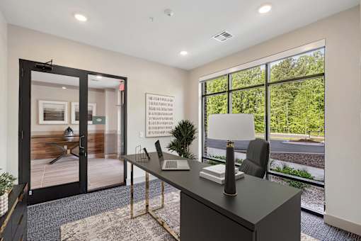 A black desk with a lamp and a plant on it in a room with a glass door at Vintage Raleigh West Apartments, North Carolina