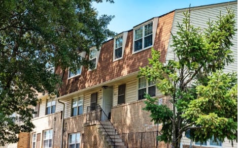 A brown building with a tree in front of it at Pleasantview Apartments, Baltimore