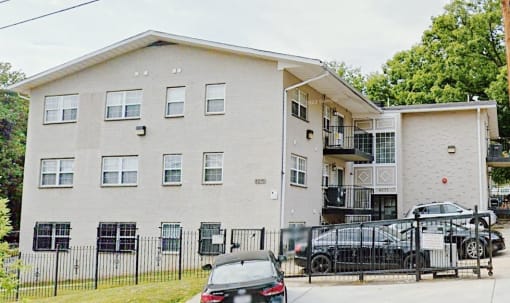 a picture of a three story apartment building with a black car parked in front of it