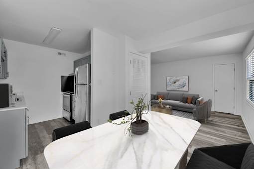 A modern kitchen with a white table and a grey couch.