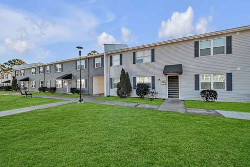 A row of modern townhouses with a green lawn in front.