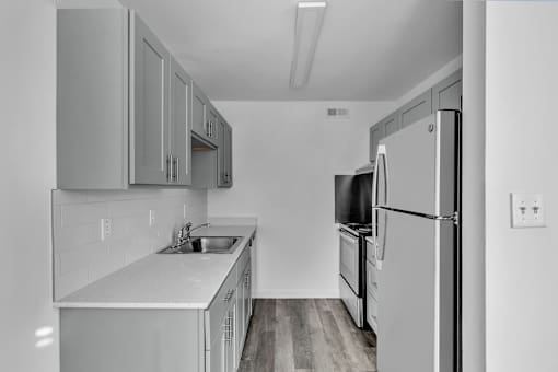 A kitchen with a refrigerator, sink, and cabinets.