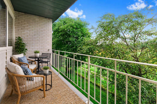 A balcony with a table and chairs overlooking a green lawn.