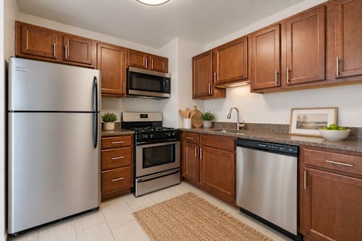 A kitchen with a refrigerator, microwave, oven, and sink.