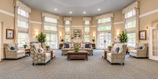A spacious living room with a carpeted floor and large windows.