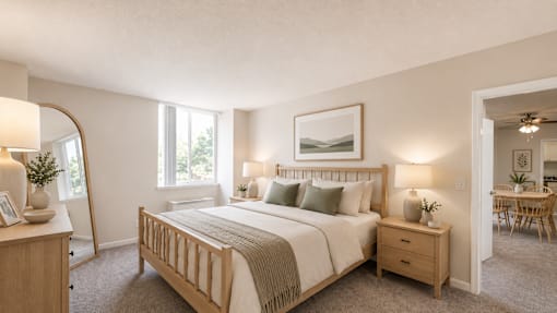 A bedroom with a large bed, nightstand, and a painting on the wall.