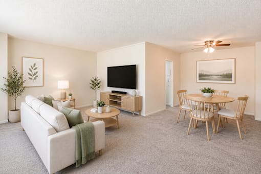 A living room with a white couch, a wooden coffee table, and a television.