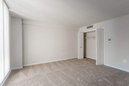 A room with a carpeted floor and a doorway leading to another room at Charlestowne North Apartments, Greenbelt, MD
