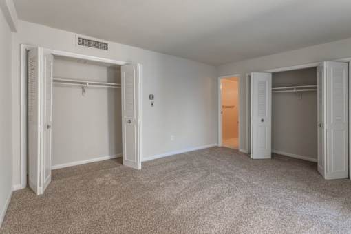 A room with white walls and carpeted floor with four open closets at Charlestowne North Apartments, Greenbelt, MD