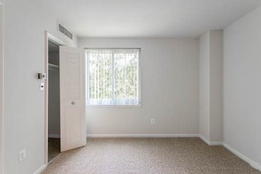 A room with a carpeted floor and a window with blinds at Charlestowne North Apartments, Maryland