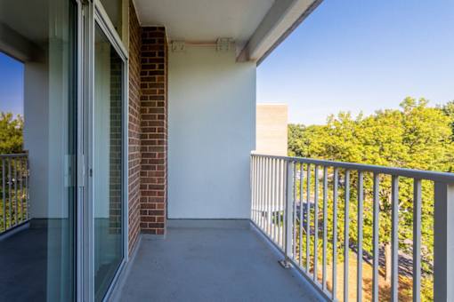 A balcony with a glass door and a metal railing at Charlestowne North Apartments, Greenbelt, Maryland