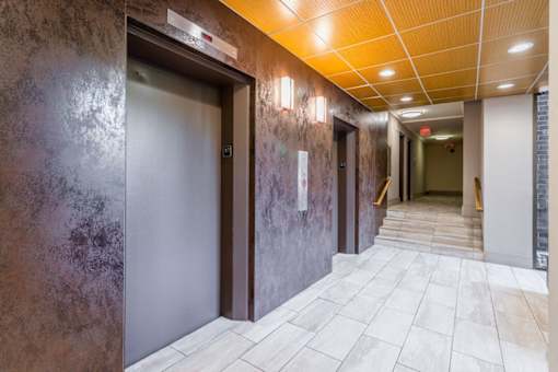 A hallway with a brown wall and a white tiled floor at Charlestowne North Apartments, Greenbelt, MD